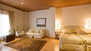 Een slaapkamer met een houten plafond, een bed met hoofdeinde, een bank, een bijzettafeltje en een vloerkleed.