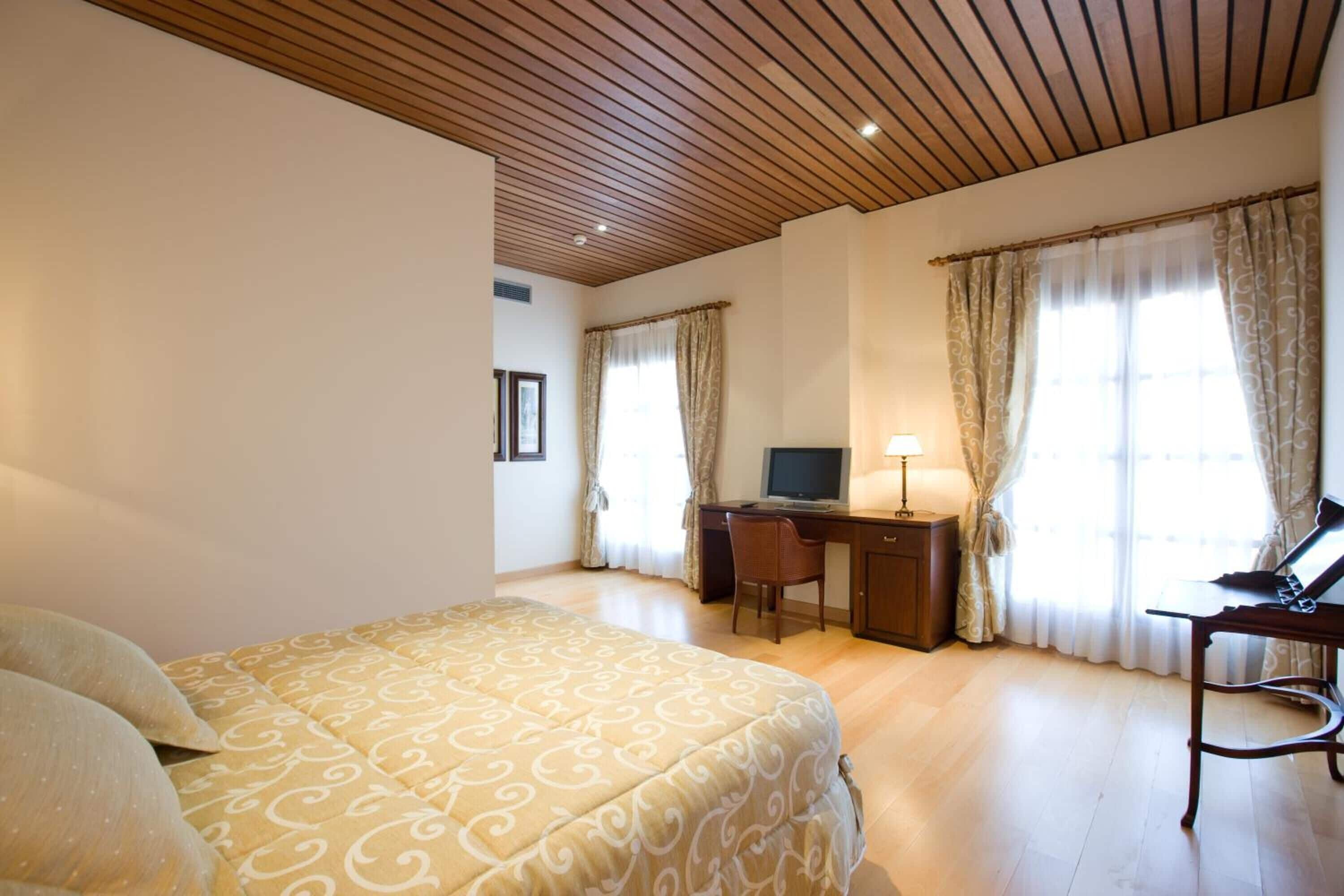 Una habitación de hotel con cama, escritorio, silla y cortinas.