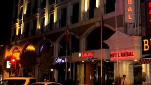 Un hotel de varios pisos con señalización iluminada, incluyendo “HOTEL ANIBAL” y “RAMADA”.