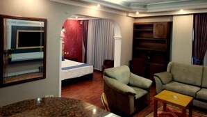 Una habitación de hotel con cama, sofá, una mesita y espejo.