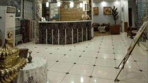 Un vestíbulo amplio con un mostrador de recepción curvo, suelo de baldosas y una escalera.