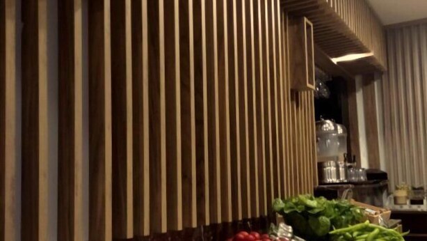 Una mesa de buffet con diversos alimentos y una cocina moderna al fondo.
