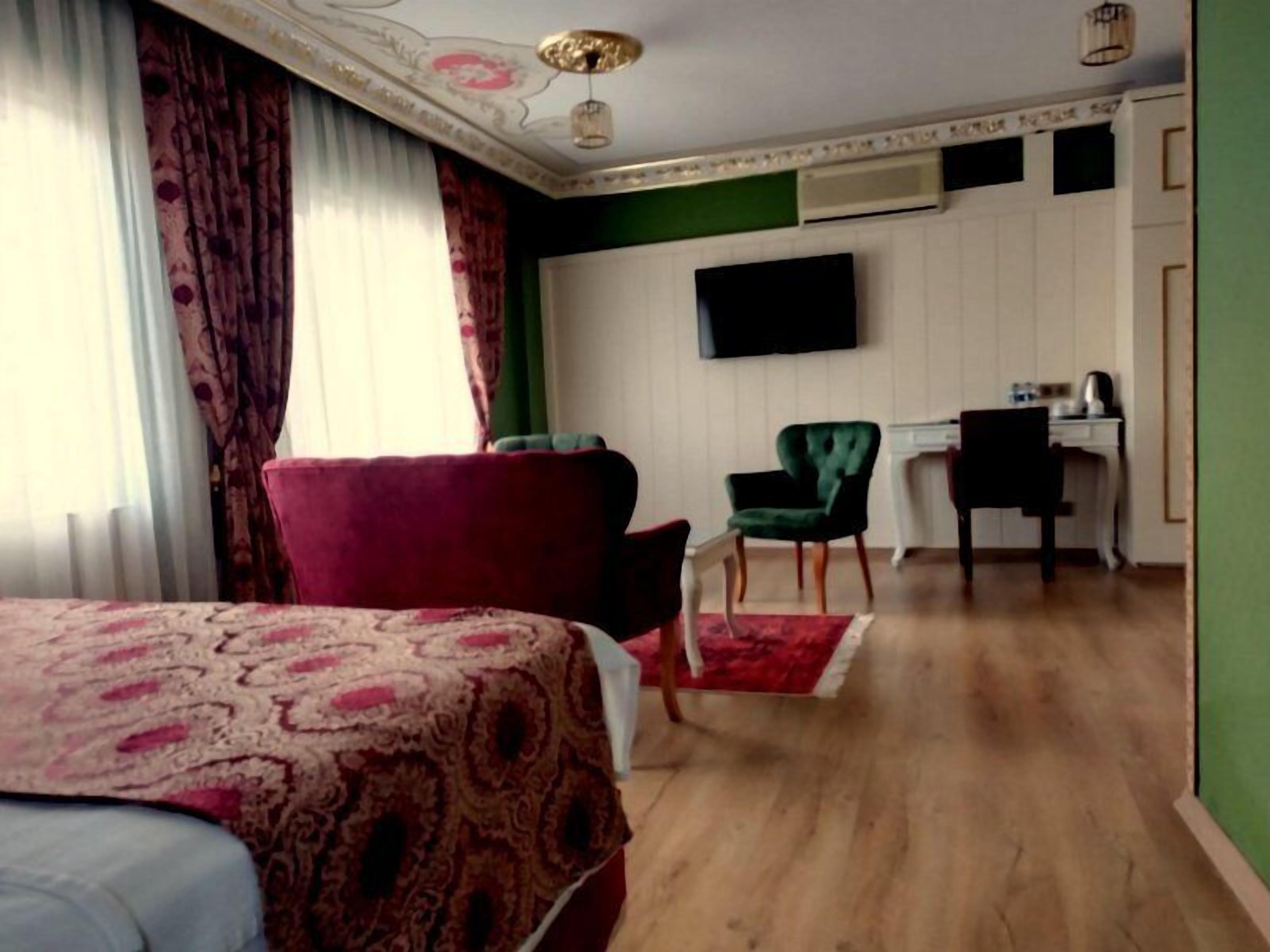 A hotel room with a bed, a desk, a chair, and a television on the wall.
