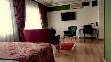 A hotel room with a bed, a desk, a chair, and a television on the wall.