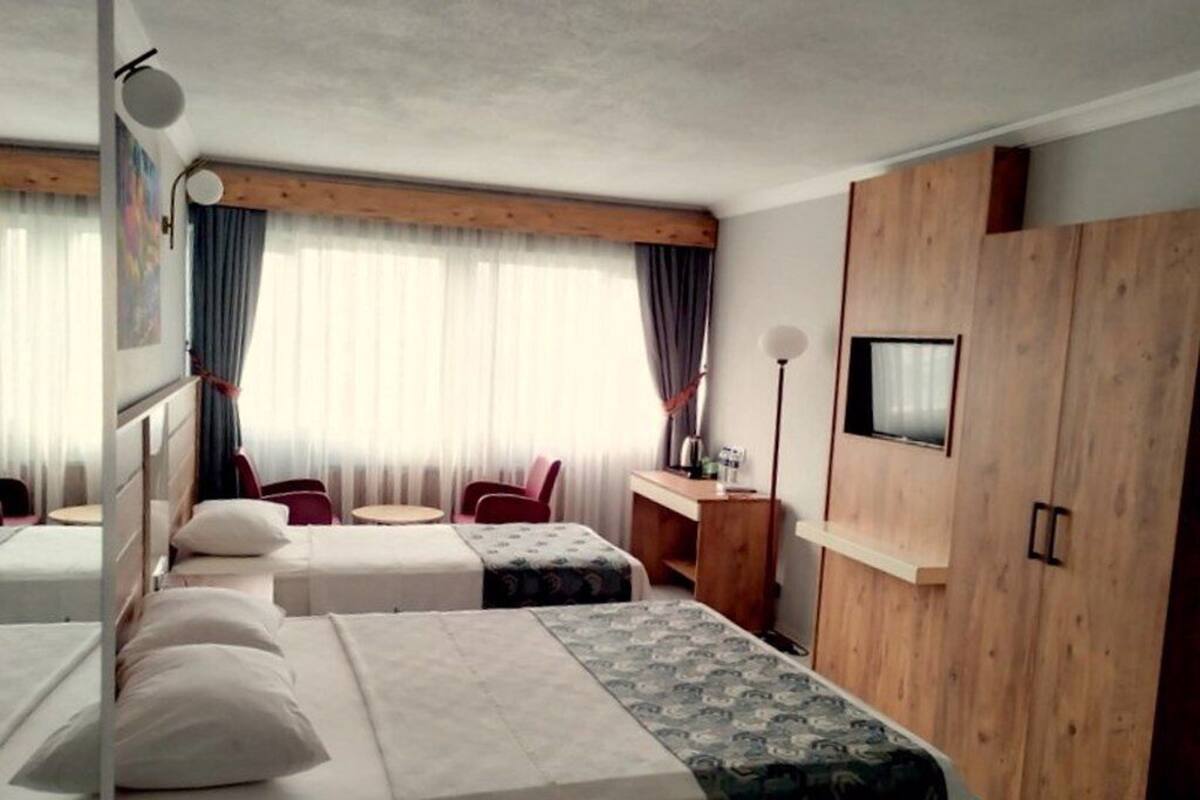 A hotel room with two beds, a desk, a chair, and a wardrobe.