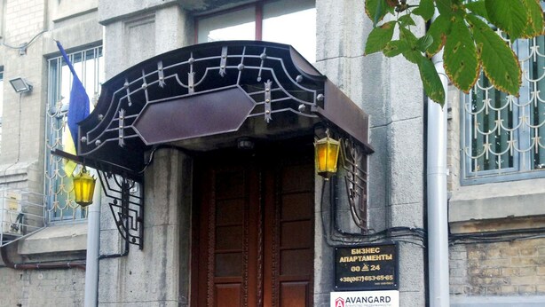 Un bâtiment doté d’une porte à deux battants de couleur marron, d’un auvent en métal et d’une enseigne indiquant qu’il s’agit d’un immeuble commercial.
