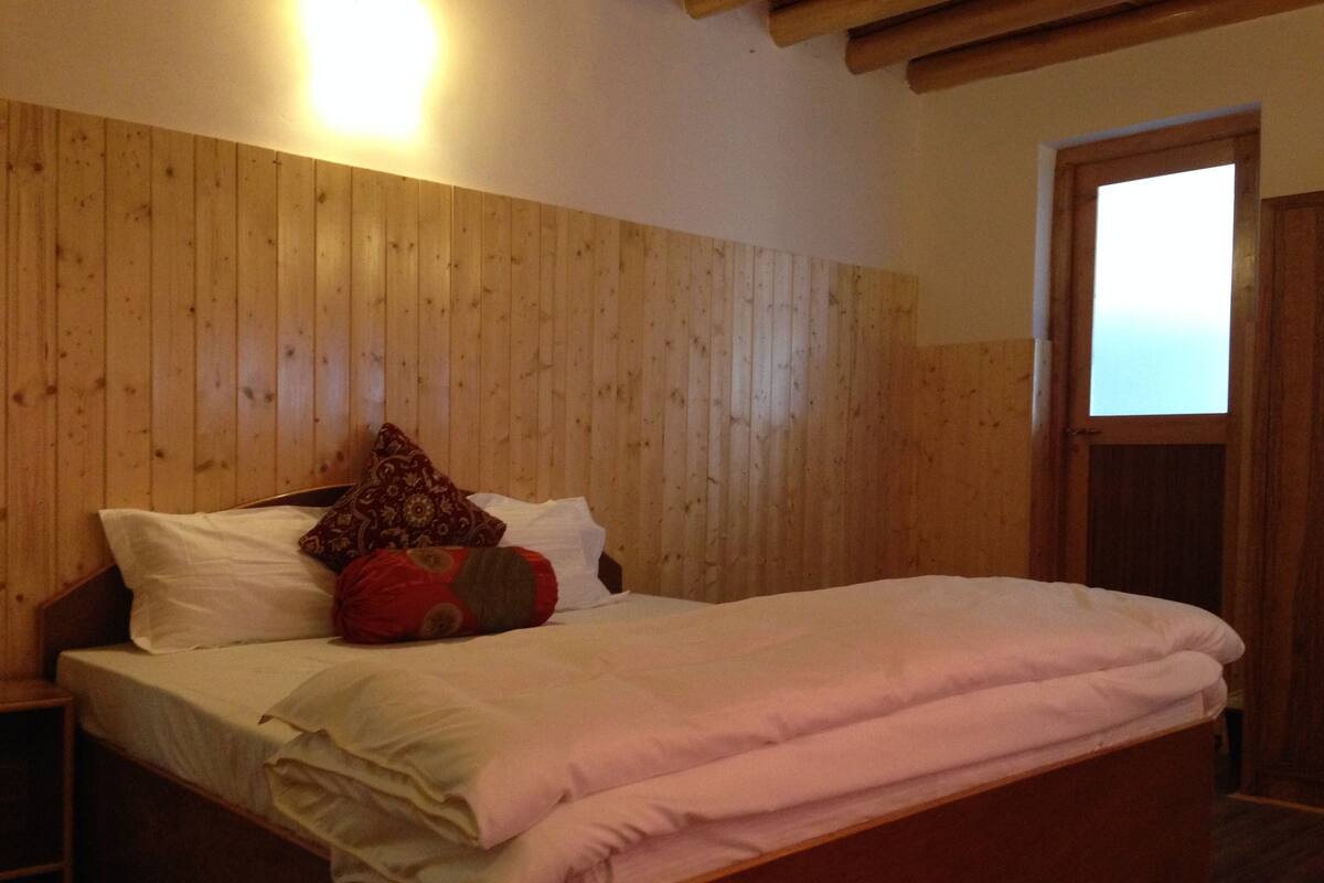 A wooden-paneled bedroom with a bed, pillows, and a nightstand.