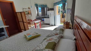 A compact bedroom with a bed, a small kitchenette, and a view of the outdoors. - Bangalô Red Moon (Florianópolis)