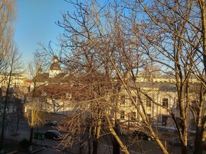 A view of a building with a dome and a tower, surrounded by bare trees and parked cars.