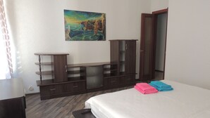 A bedroom with a bed, a wardrobe, a painting on the wall, and a window with curtains. - Podol Apartment (Kyiv)