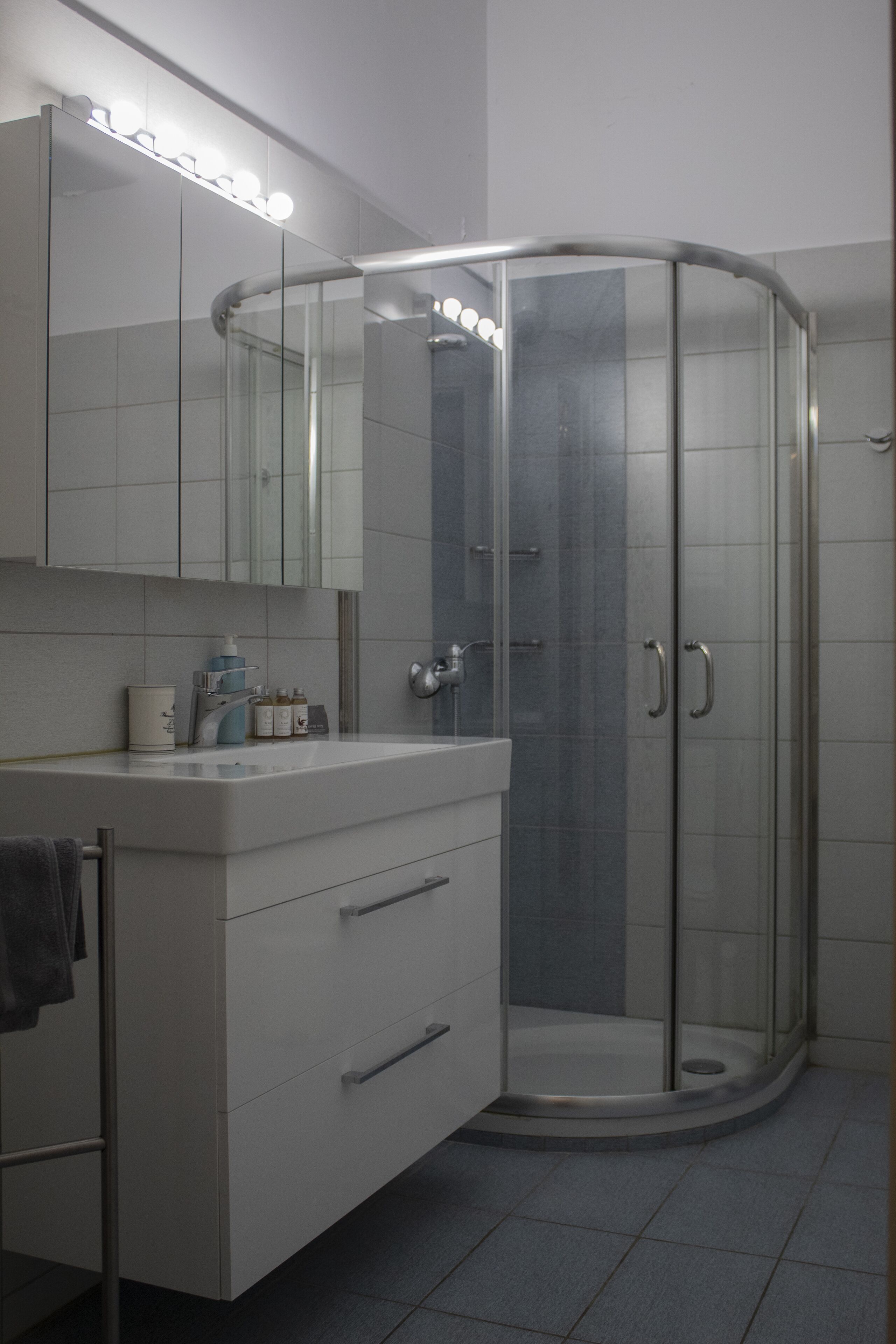A modern bathroom with a glass shower enclosure, a vanity with a mirror, and a sink.