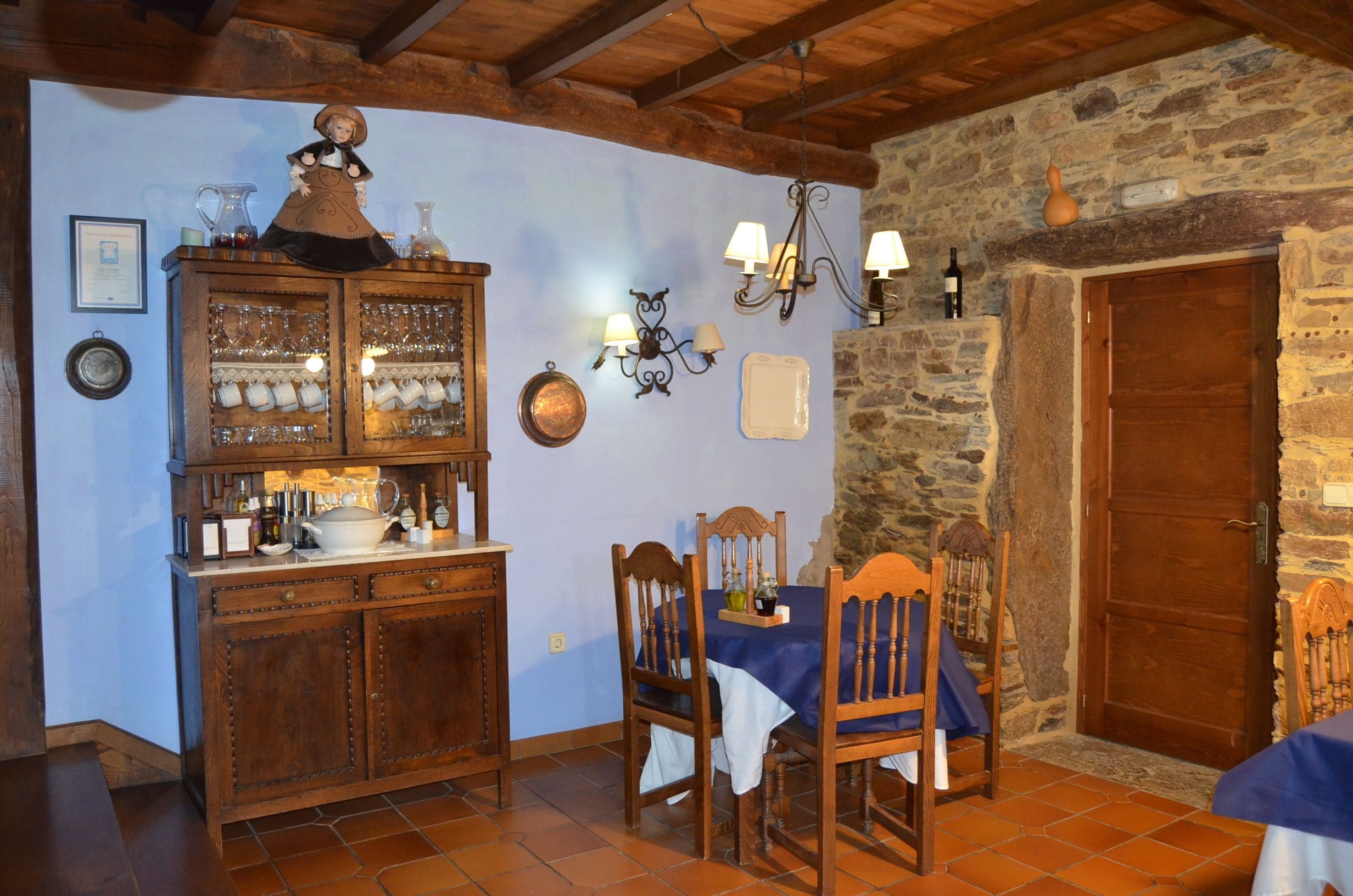 Un coin repas rustique avec un buffet en bois, une table, des chaises et un mur en pierre.