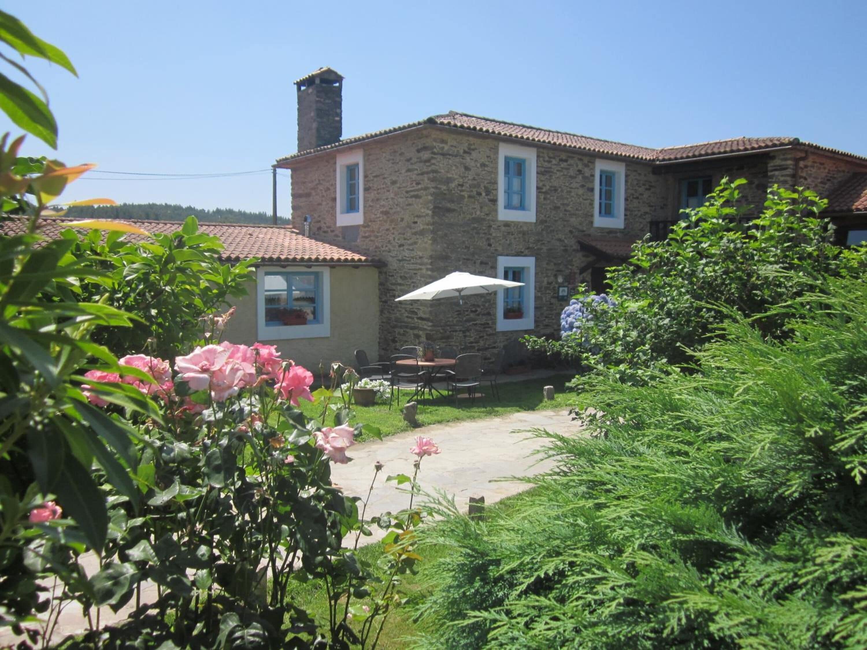 A stone building with a tiled roof, a chimney, and a small patio with outdoor seating.