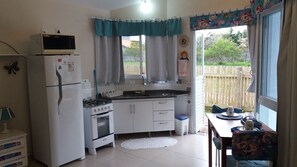 Eine kompakte Küche mit Kühlschrank, Herd, Spüle und einem Essbereich mit Tisch und Stühlen.
