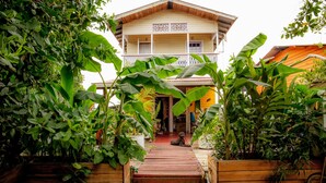 A wooden house with a balcony, surrounded by lush greenery. - Barrbra BnB Over The Sea (Bocas del Toro)
