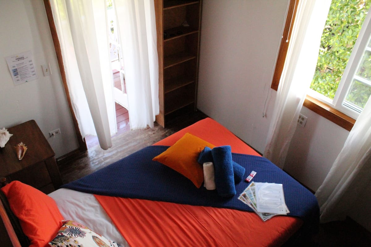 A bedroom with a bed, a nightstand, a wardrobe, and a window with a view of greenery.