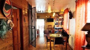 A wooden interior with a dining area, a bookshelf, and a door with decorative elements. - Barrbra BnB Over The Sea (Bocas del Toro)