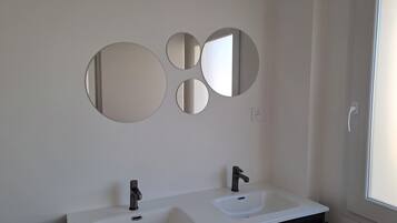 Un baño con dos lavamanos, un espejo y una ventana.