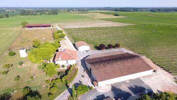 A large building with a red roof, surrounded by green fields and trees.