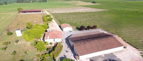 A large building with a red roof, surrounded by green fields and trees.