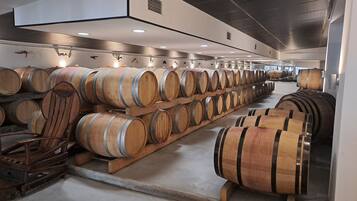 Un'area di stoccaggio con file di botti di legno, probabilmente per vino o liquori, in un ambiente di magazzino.