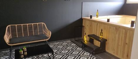 Un baño moderno con tocador de madera, alfombra estampada en blanco y negro y un banco tejido.