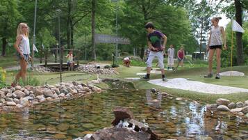 A golf course with a pond, trees, and people playing golf.