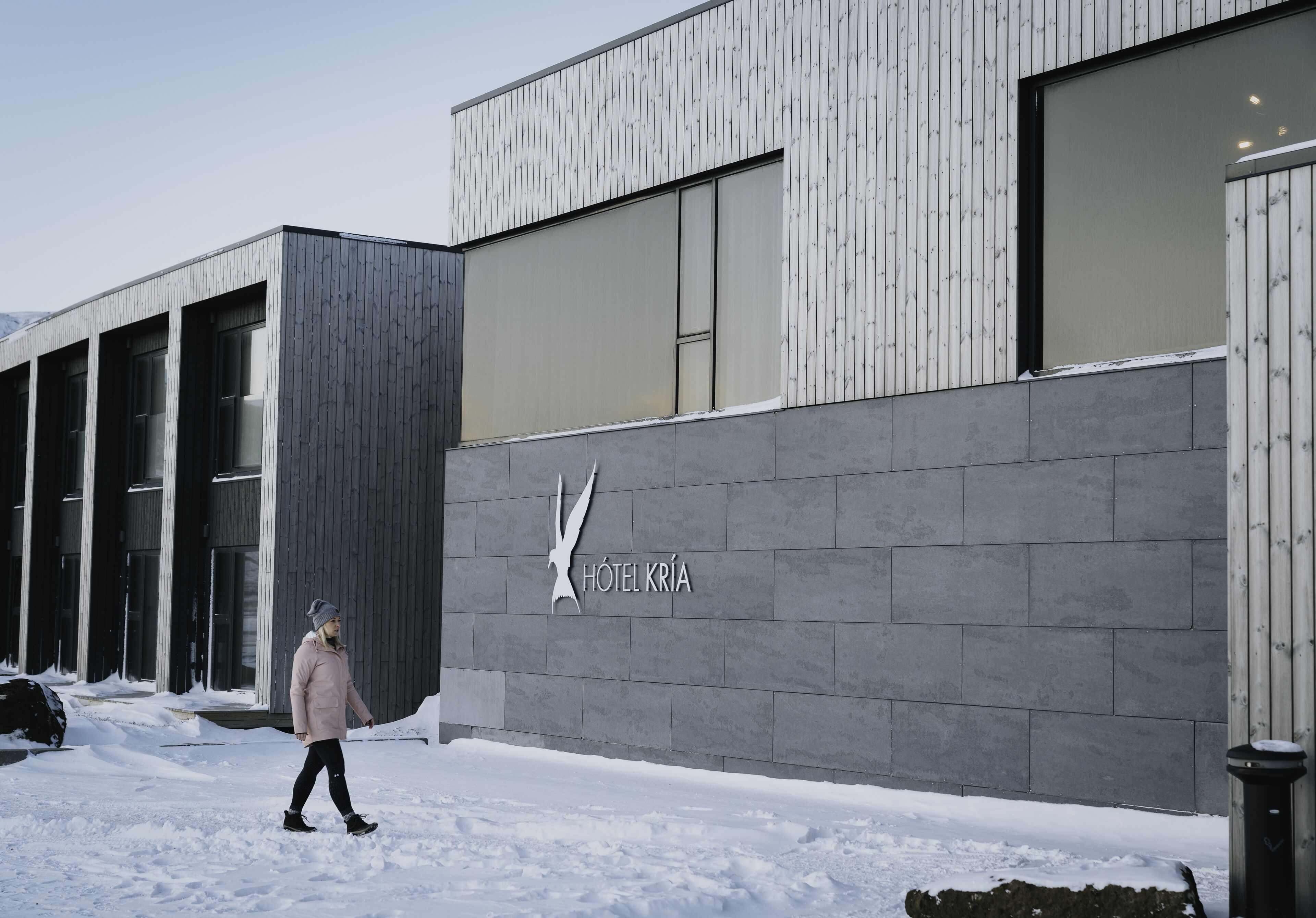 A modern building with a large logo of a bird and the text "HOTEL KRÍA" on the facade.
