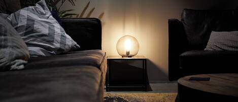 A dimly lit room with a sofa, a small table, and a lamp on a side table.