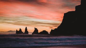 Un atardecer costero con formaciones rocosas silueteadas contra el cielo.