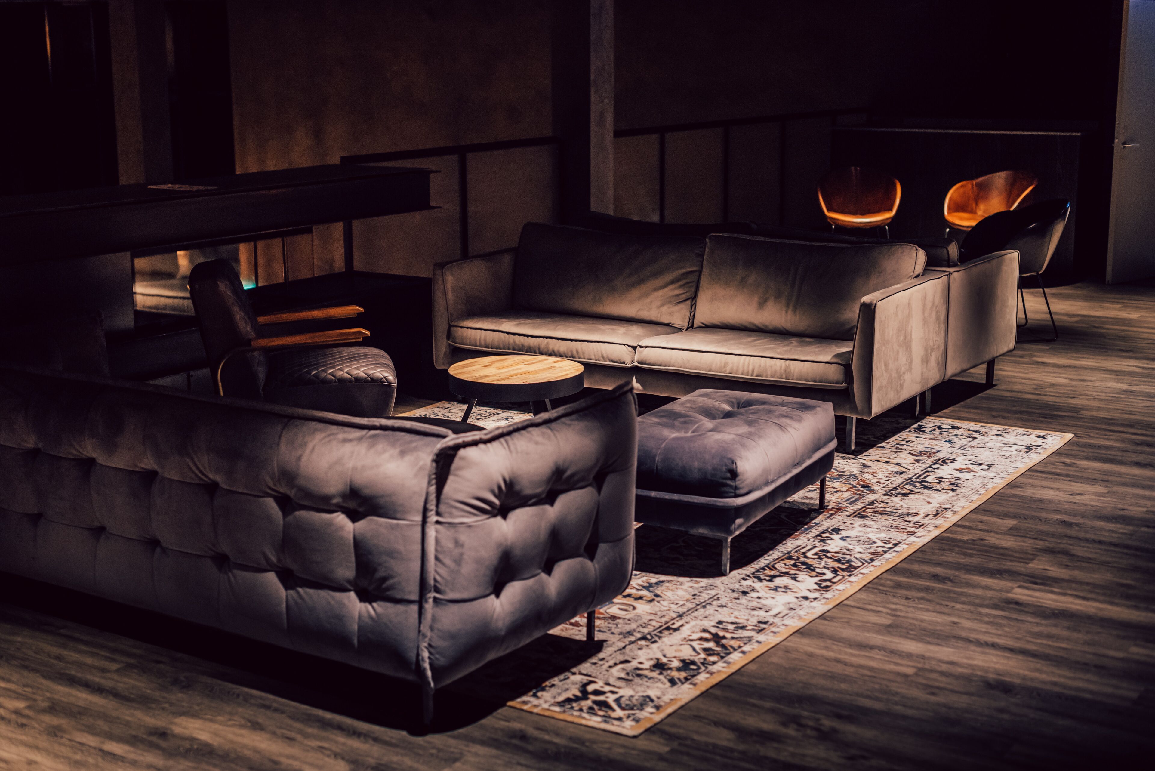 A modern living room with a sectional sofa, a small round coffee table, and two armchairs.