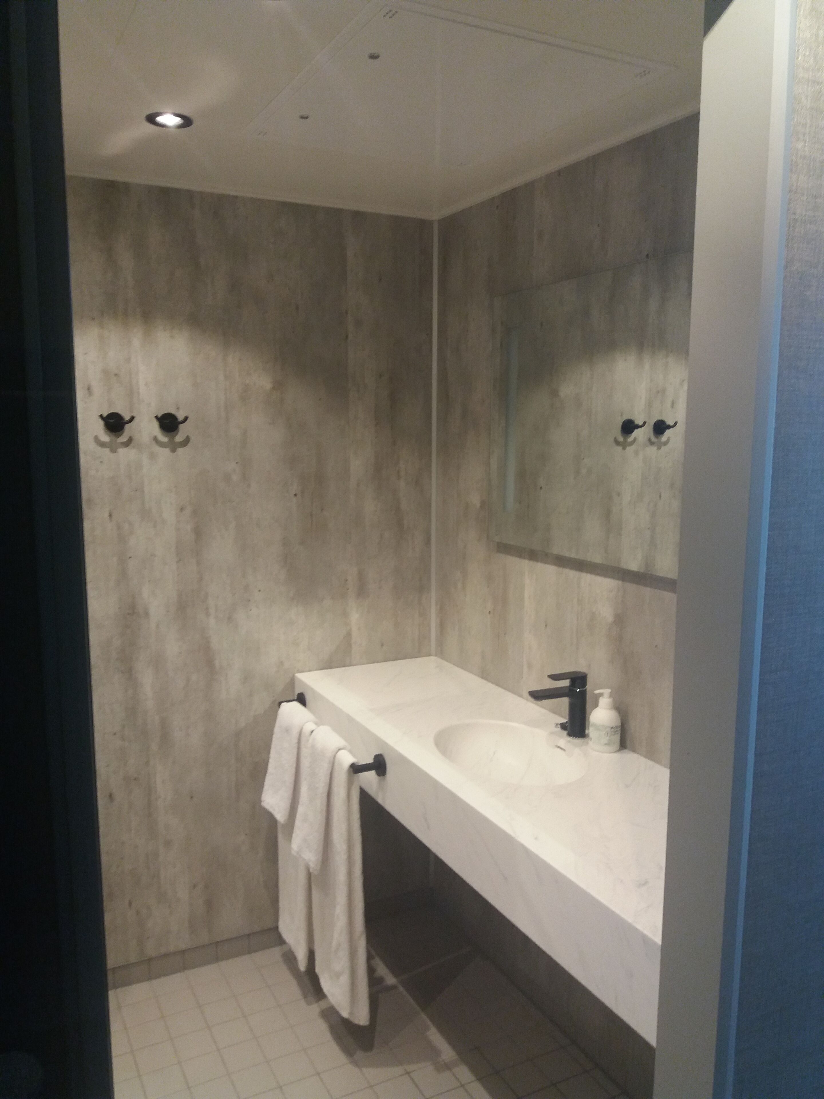 A modern bathroom with a large mirror, two sinks, and a towel hanging on the wall.