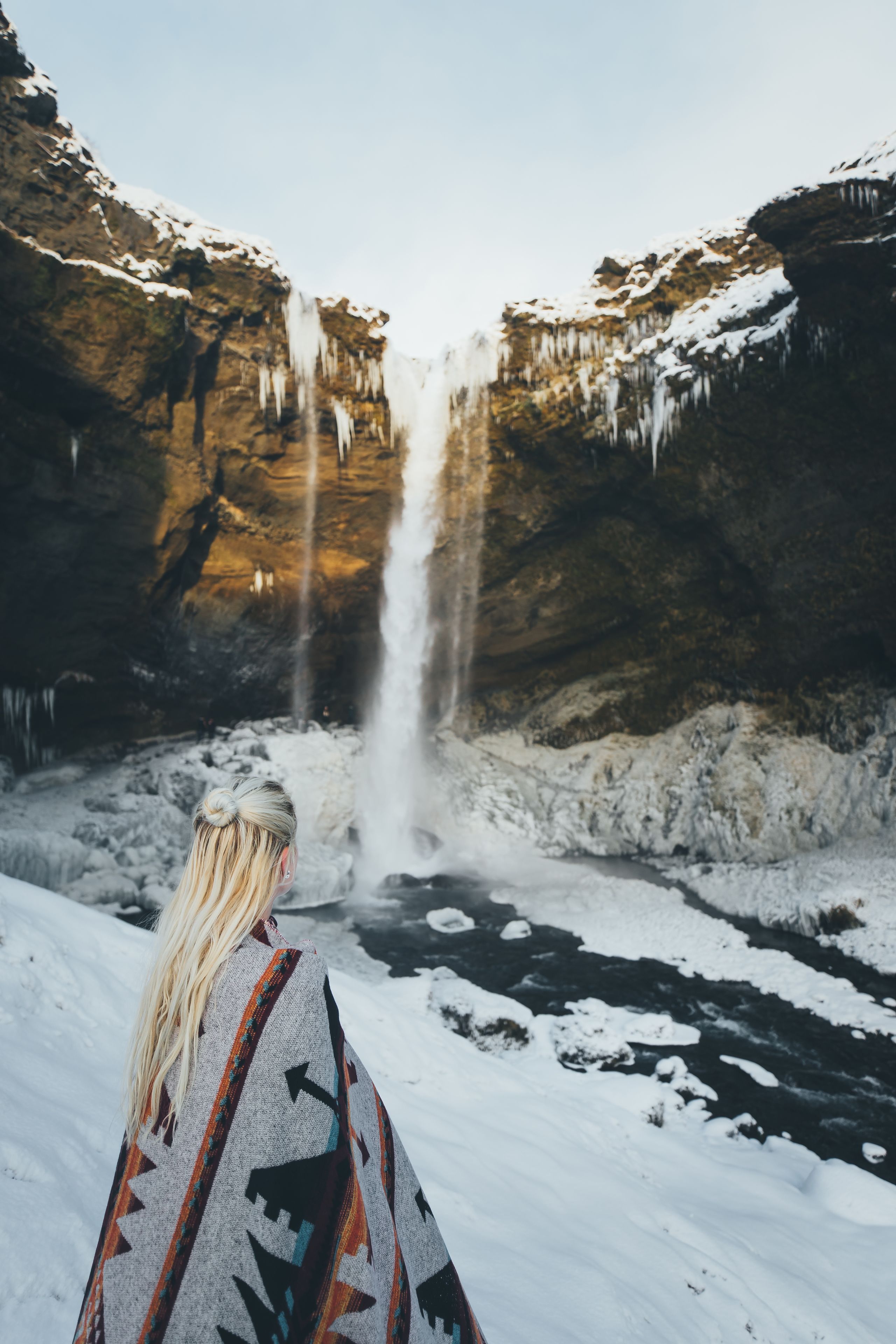 A person standing in a snowy landscape with a waterfall.