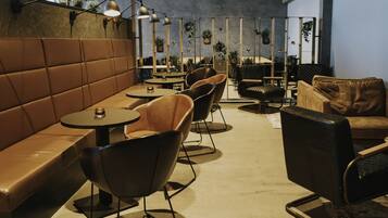 A modern lounge area with leather seating, tables, and hanging plants.