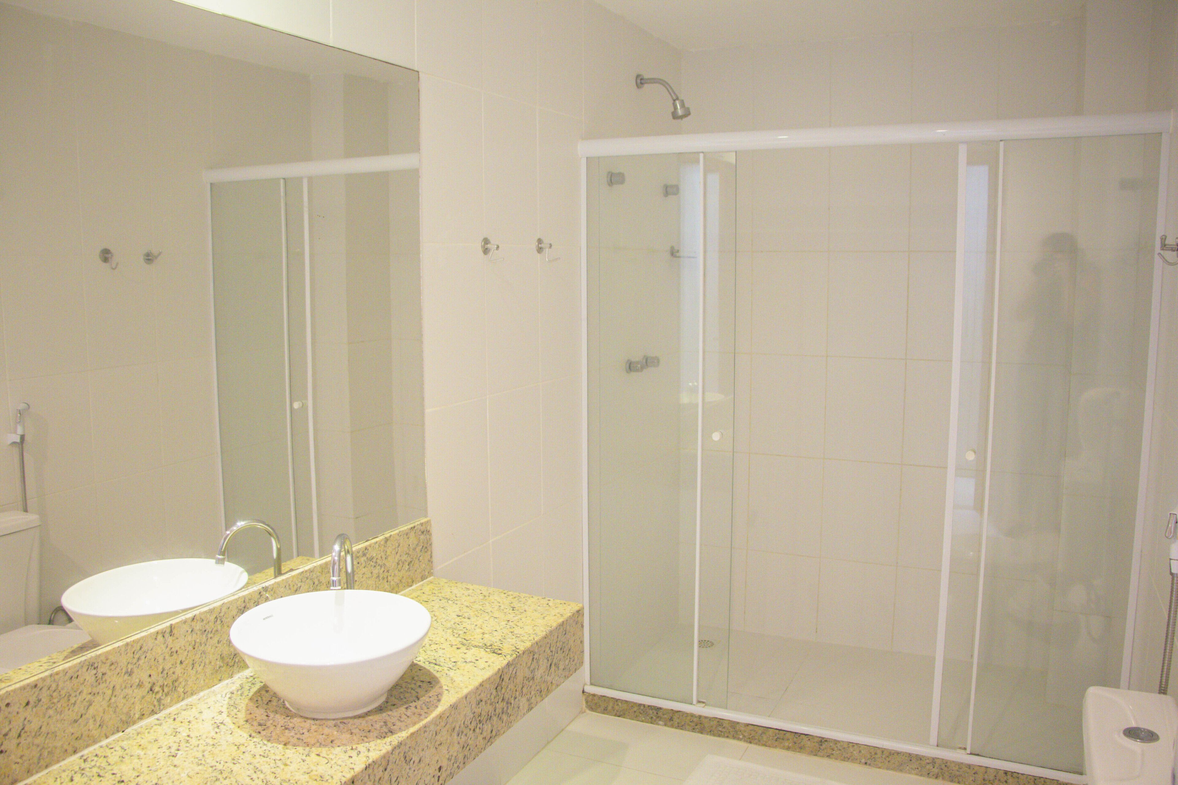 Un baño con lavamanos doble, un espejo grande y una ducha con mampara de vidrio.