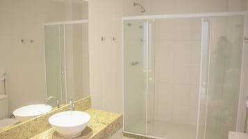 Un baño con lavamanos doble, un espejo grande y una ducha con mampara de vidrio.