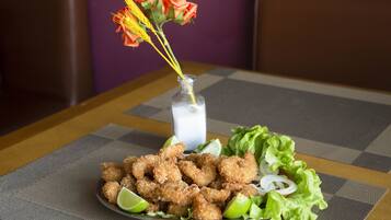 Un plato de camarones fritos con cuñas de limón y lechuga sobre un mantel a cuadros.