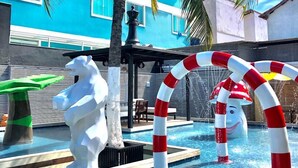 Una piscina con detalles decorativos, una palmera y un edificio con paredes exteriores azules y blancas.