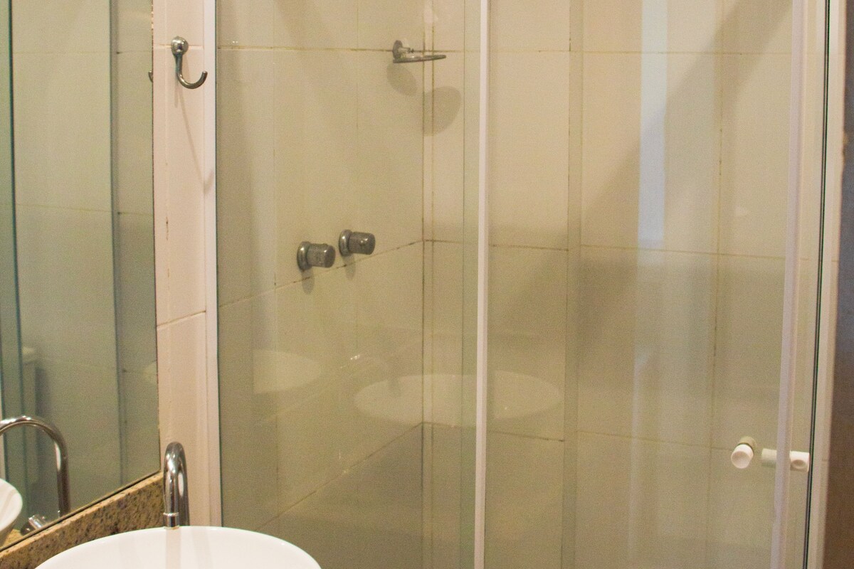 A bathroom with a glass-enclosed shower, a white sink, and a mirror.