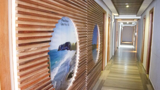 Un pasillo con listones de madera y un muro espejado que muestra una vista panorámica de la playa.
