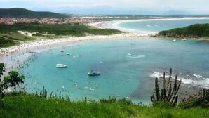 Un paisaje costero con playa, barcos y una ciudad a lo lejos.