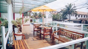 Una terraza de madera con mobiliario exterior y un paraguas amarillo.