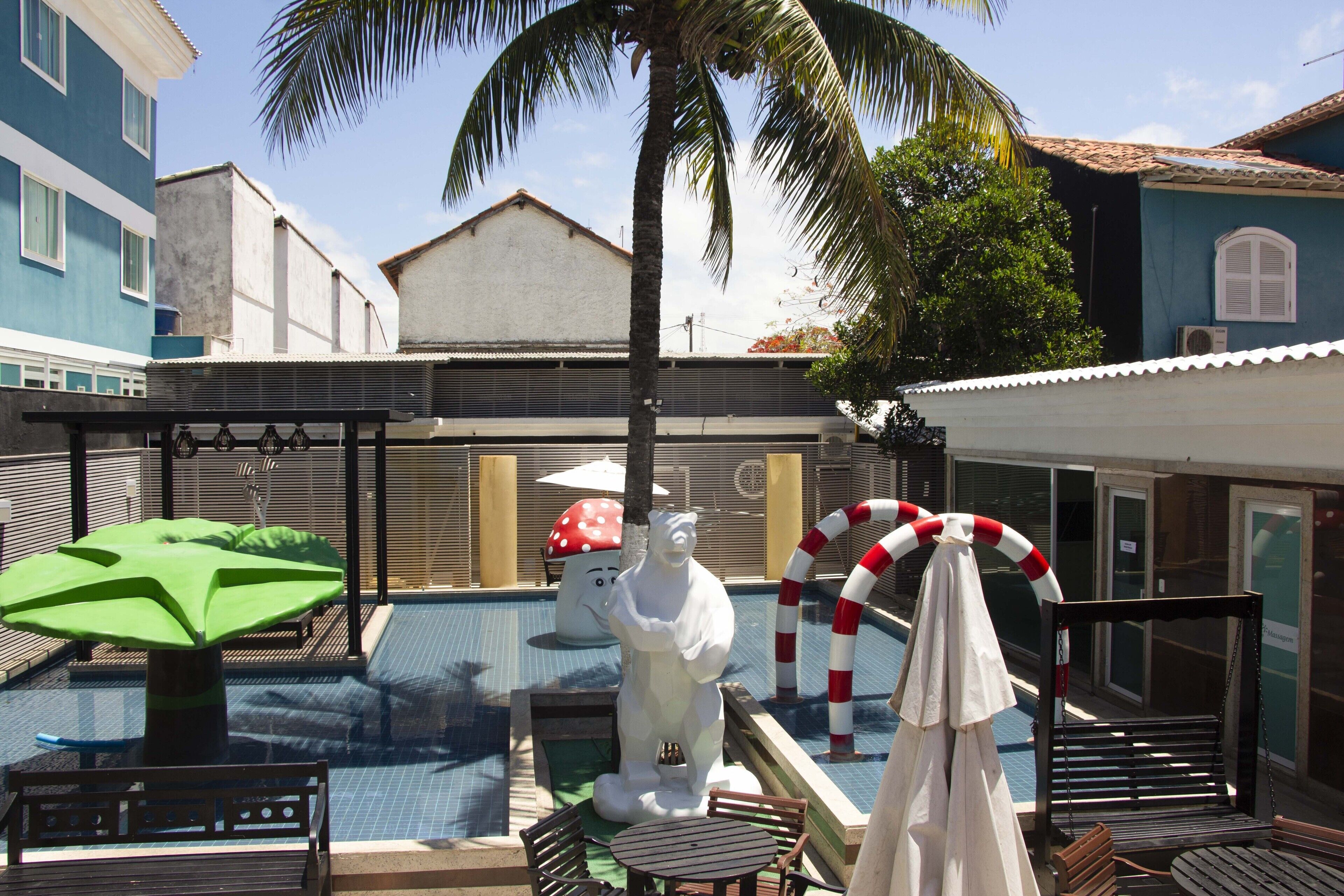 A pool area with a statue, lounge chairs, and umbrellas.