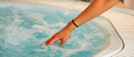 A person reaching into a hot tub filled with water.