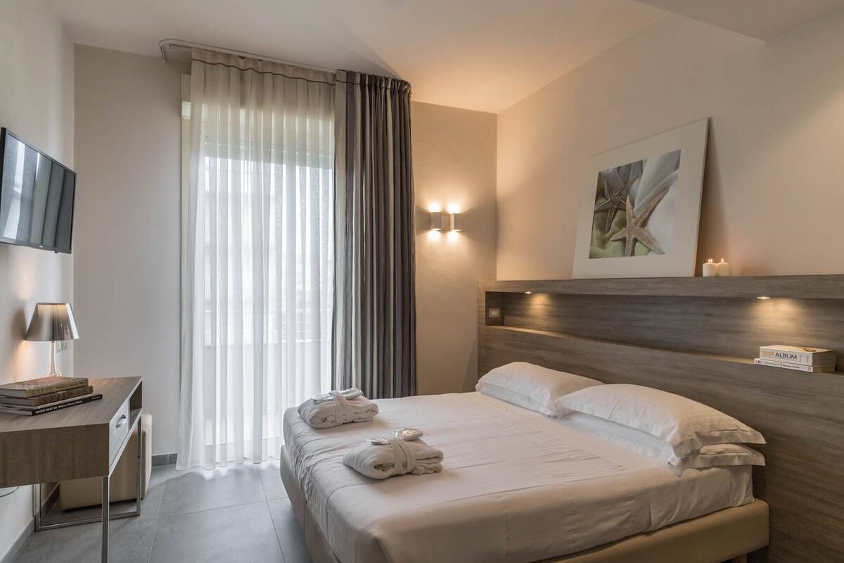 Ein Hotelzimmer mit Bett, Nachttisch, Lampe und einem Bild an der Wand.