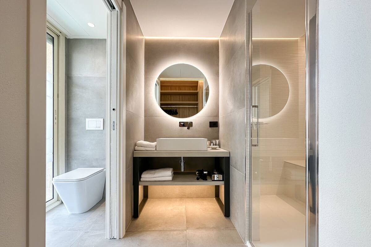 Ein modernes Badezimmer mit integriertem Waschbecken, Toilette und einer Duschkabine aus Glas.