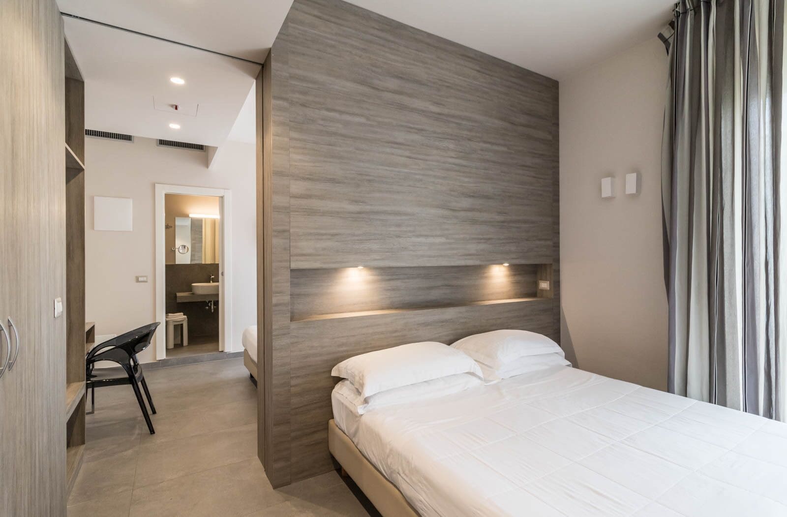 Ein modernes Hotelzimmer mit einem großen Bett, einem Schreibtisch und einem durchgegangenen Badezimmer.