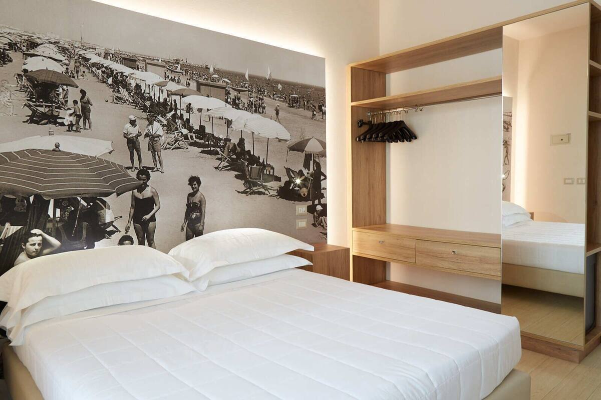 Ein Hotelzimmer mit einem großen Bett, einem Holzschrank und einem Wandgemälde im Strandhausstil.