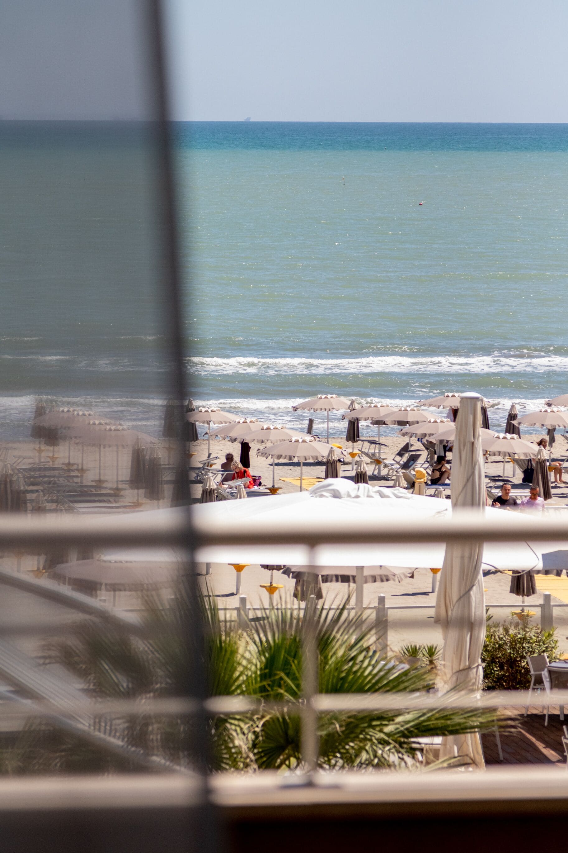 A beach view with umbrellas and chairs, a clear sky, and the ocean.