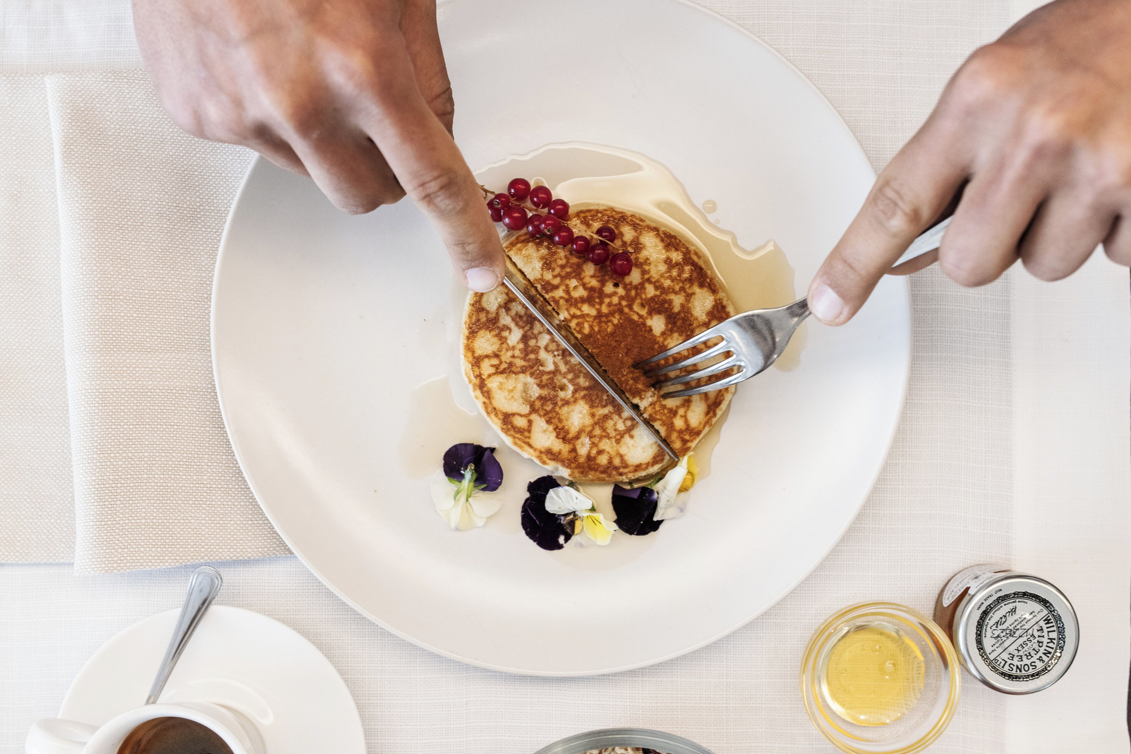 A plate with pancakes, syrup, and berries.
